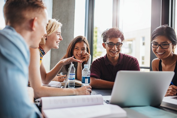 A group of interns at a conference table looking at a computer.